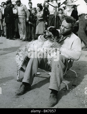 ROD STEIGER relaxes between takes of the 1957 Rank film Across The Bridge with co-star spaniel Dolores Stock Photo