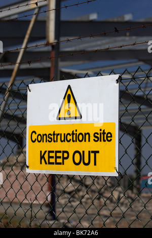 construction site keep out sign on a chain link fence surrounding a redevelopment building site with old factory Stock Photo