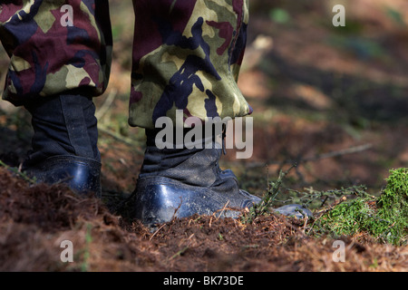 man wearing camouflage combat trousers and boots standing in a forest in the uk Stock Photo