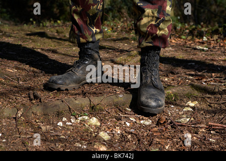 man wearing camouflage combat trousers and boots standing in defensive stance in a forest in the uk Stock Photo