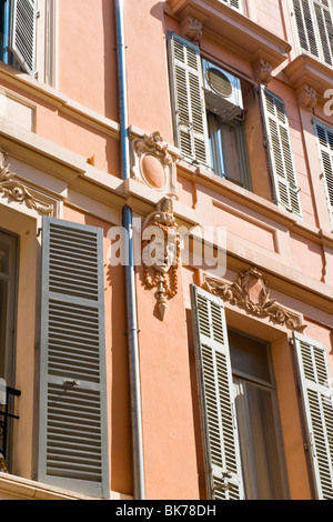 Cannes , Rue D'Antibes , building or house detail , grotesque face or head sculpture or statue surrounded by windows & shutters Stock Photo