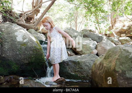 Girl standing on rock in river Stock Photo