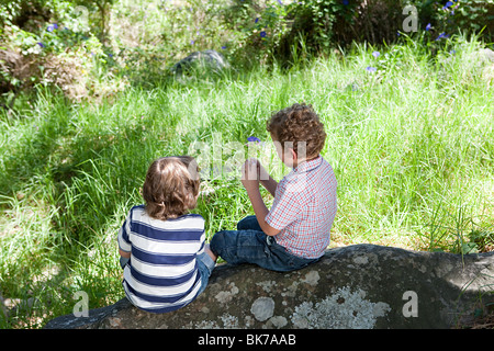 Two boys sitting on a rock Stock Photo