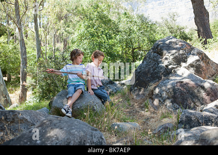 Boys sitting on rocks with stick Stock Photo