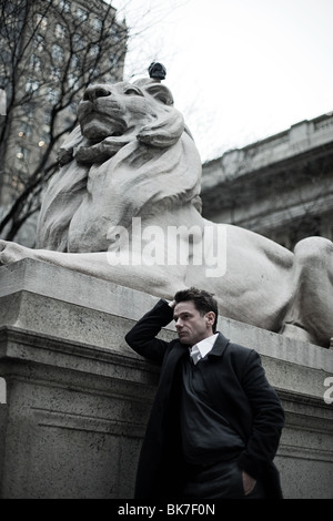 Man by lion statue at new york public library Stock Photo