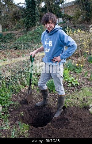 Model released teenage boy digging hole in garden Stock Photo