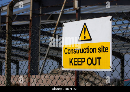 construction site keep out sign on a chain link fence surrounding a redevelopment building site with old factory Stock Photo