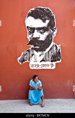 ironic juxtaposition peasant woman & street art depiction Emiliano Zapata revolutionary leader reformer for peasant land rights Stock Photo