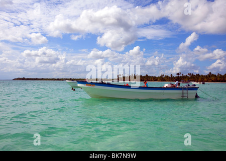 a small tourist boat moored up in shallow water near the coast in the Caribbean sea Stock Photo