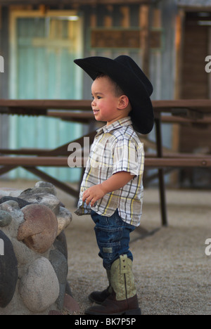 A cute 2-4 year old mixed race boy wearing cowboy boots and hat (Released) Stock Photo
