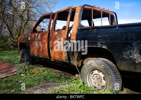 An old rusty burned out pickup truck abandoned on waste ground. Stock Photo