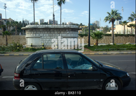 A woman Muslim  read the newspaper inside his car on the roadside of Beirut Lebanon Stock Photo