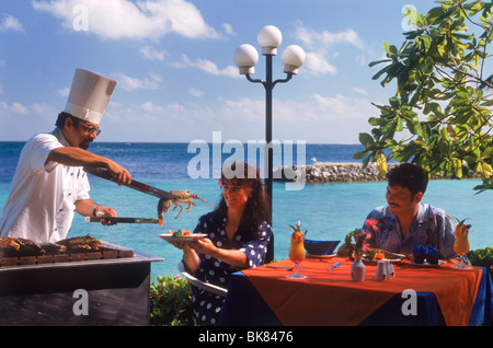 Grilled seafood and lobster served at outdoor restaurant by chef on Fihalhohi Island in the Maldive Islands in Indian Ocean Stock Photo