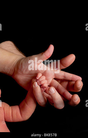 Parents' hands hold the fingers of newborn baby The hand of a mother ...