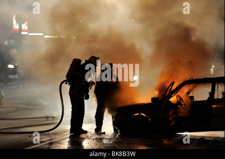 Firefighters extinguishing a burning car Stock Photo