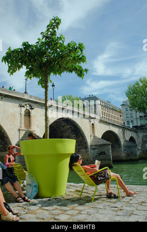 People Enjoying 'Paris Plages' Urban Beach on 'Seine River' Paris France, Summer Festivals, Lounge Chairs, Potted Trees, teens on hot day [Teenager] Stock Photo