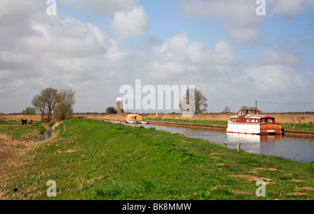 Rowing and moored cruisers in the Cut between Martham Broad and West Somerton Staithe, Norfolk, United Kingdom. Stock Photo