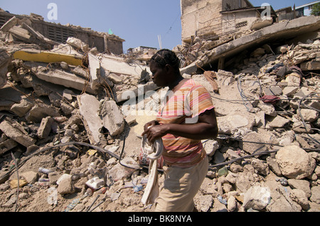 Pedestrian walk past a building that collapsed in Port-au-Prince after a 7.0 magnitude earthquake struck Haiti on 12 January 2010 Stock Photo