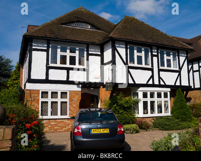 Mock Tudor black and white 1930's house with garage and a drive, in Esher, Surrey. UK. Photograph taken on a sunny day with sun and blue sky. Stock Photo