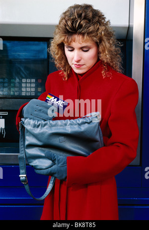 Woman performing a bank transaction at an ATM, Automated Teller Machine. Stock Photo