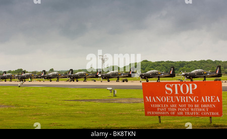 Stationary Tucano planes at RAF Linton-On-Ouse training base, with a Stop warning sign in the foreground Stock Photo