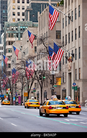 Taxi cabs race down flag-lined 5th Avenue in Manhattan, New York City USA Stock Photo