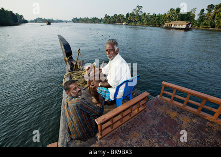 Houseboat captain steering his kettuvallam boat in backwaters of Kerala, India. Stock Photo