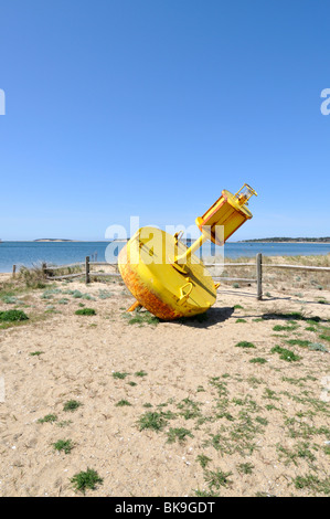 Yellow channel marker beached  in Wellfleet Harbor, Cape Cod USA. Stock Photo