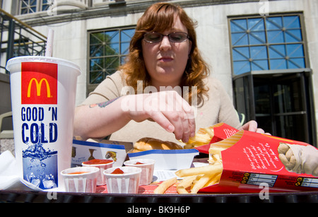 Overweight woman eating McDonald's fast food meal Stock Photo