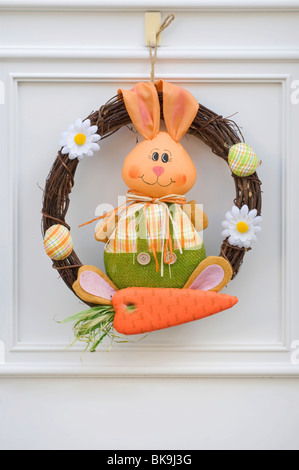 Easter wreath, Easter bunny with carrot on white door Stock Photo