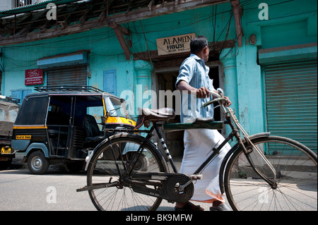 Local Man walking past warehouse store near the waterfront, Fort Cochin, Kerala, India Stock Photo