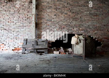 A damaged brick wall in an old abandoned factory with a big hole in it Stock Photo