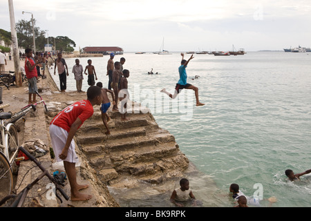 Boys swimming in the harbour - Stonetown, Zanzibar, Tanzania. Stock Photo