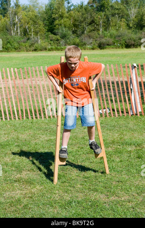 Child walking on wooden stilts learning how to balance on an object Stock Photo