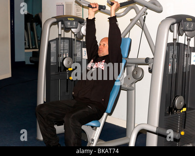 Man Excercising in Tracksuit in the Gym Using Weights Machine England Stock Photo