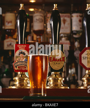 Pint of bitter served in typical atmospheric English pub with selection of traditional pump handles offering various ales Stock Photo