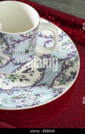 England old style tea cup and dish over red tray and blue wallpaper Stock Photo