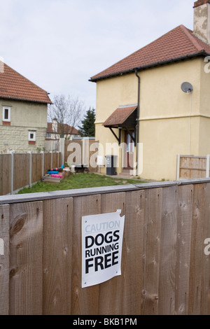 'Dogs Running Free' - a warning sign on the fence of a house in the East London suburb of Dagenham. Stock Photo