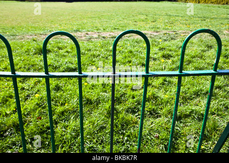 a green iron fence surrounding a park or school Stock Photo