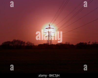 view of the sun setting behind an electricity pylon Stock Photo