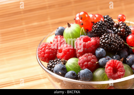 Fruit mix in the glass container, on a table from straw Stock Photo