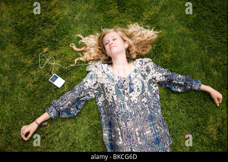 teenage girl lying on the grass listening to her i-pod Stock Photo