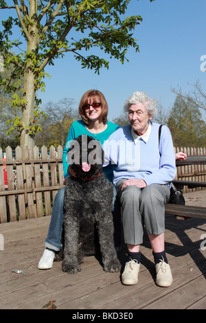 Bouvier des Flandres dog with middle aged woman and older lady sitting at table by the River Thames at East Molesey Cricket Club Stock Photo