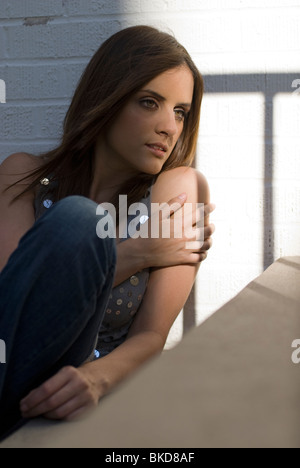 A young beautiful White Hispanic woman model sitting in a stair well Stock Photo