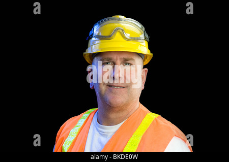 A construction utility worker wearing protective safety equipment including a hard hat, safety goggles and a reflective orange v Stock Photo