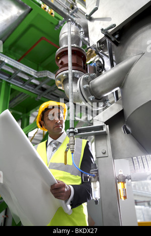 Asian factory manager wearing safety equipment checks machine Stock Photo