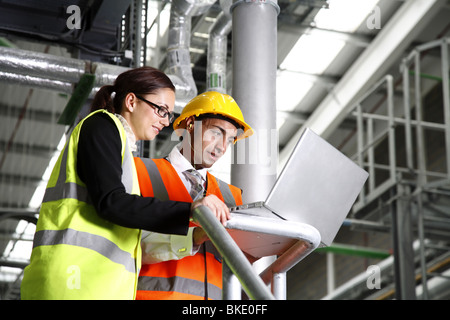 Female factory manager and asian male manager wearing safety equipment in modern factory environment Stock Photo
