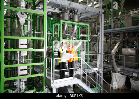 Female factory manager and asian male manager wearing safety equipment in modern factory environment Stock Photo