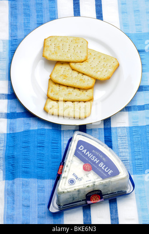 Five Tuc crackers on a white plate with a pack of Danish blue cheese Stock Photo