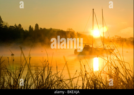A misty dawn on Lake Windermere in the Lake District UK Stock Photo